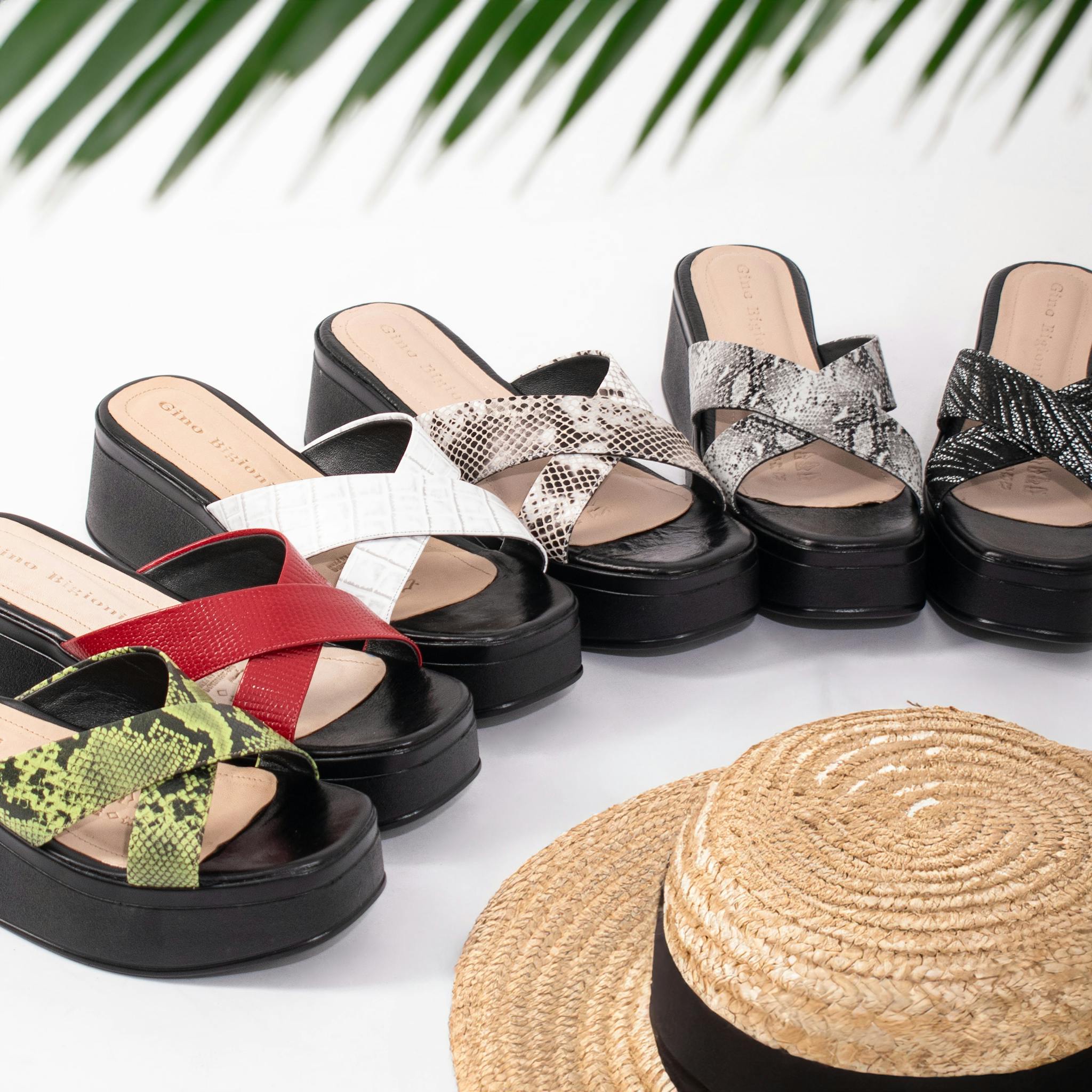 A stylish array of platform sandals in vibrant colors paired with a straw hat. Perfect summer fashion.