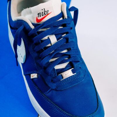 Stylish blue Nike sneaker photographed on a blue and white background, showcasing design and color contrast.