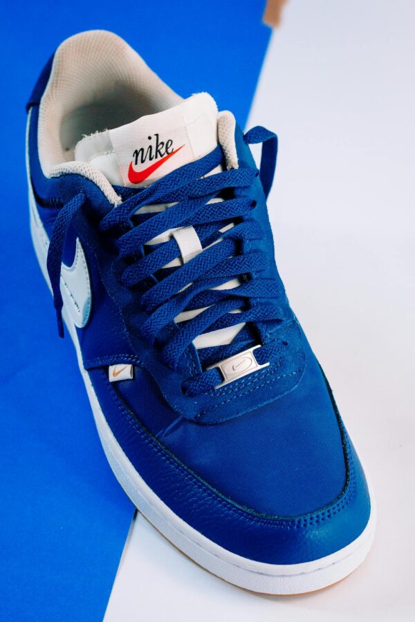 Stylish blue Nike sneaker photographed on a blue and white background, showcasing design and color contrast.